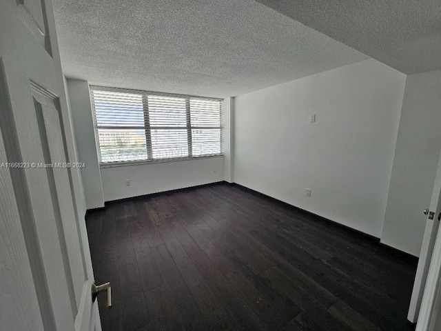 spare room featuring a textured ceiling and dark hardwood / wood-style flooring