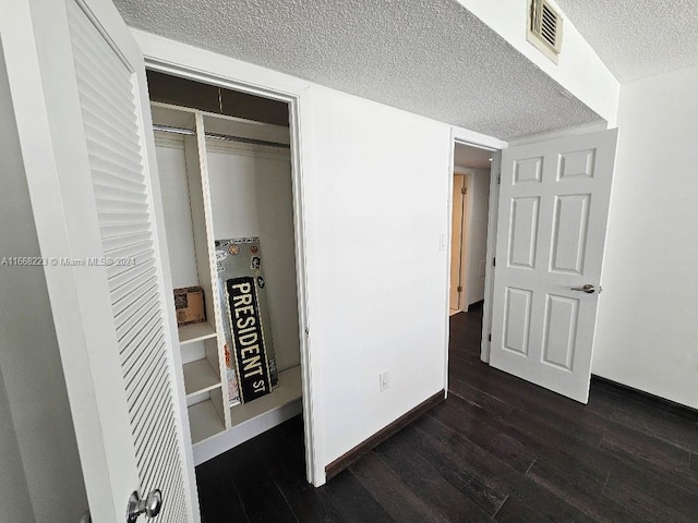 bedroom with a textured ceiling, a closet, and dark hardwood / wood-style flooring