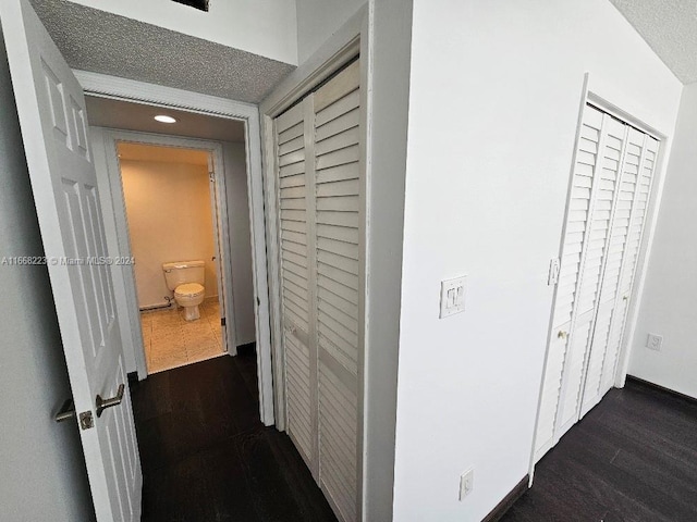 hall with a textured ceiling and dark wood-type flooring