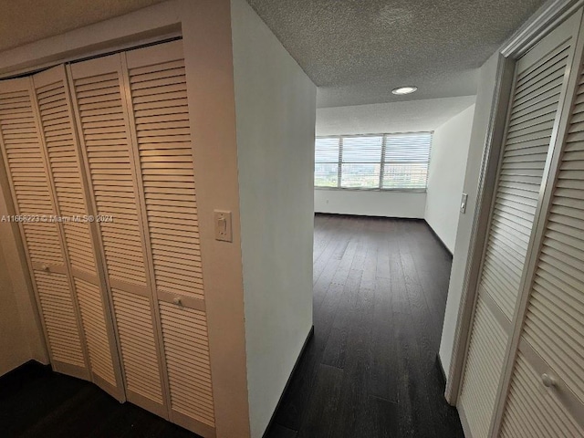 corridor with a textured ceiling and dark hardwood / wood-style flooring