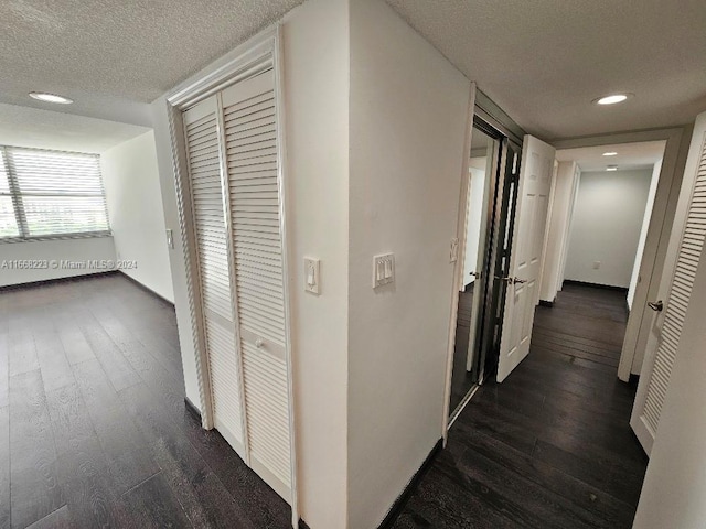 hall featuring a textured ceiling and dark hardwood / wood-style floors