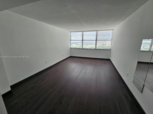 spare room featuring a textured ceiling, dark hardwood / wood-style flooring, and a wealth of natural light