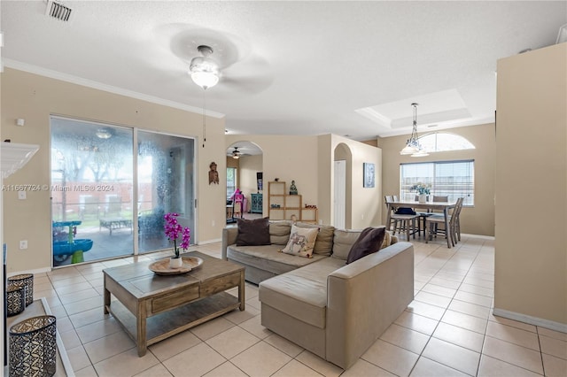 tiled living room featuring ceiling fan, a raised ceiling, and crown molding