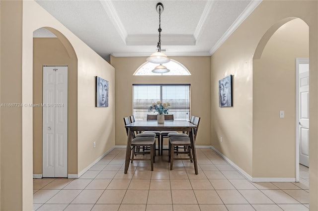 tiled dining room with a textured ceiling, crown molding, and a tray ceiling