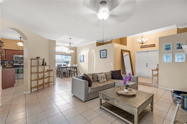 living room featuring ceiling fan with notable chandelier, light tile patterned flooring, and crown molding