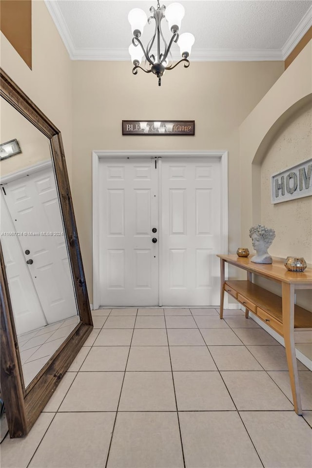 foyer with ornamental molding, a chandelier, a textured ceiling, and light tile patterned floors