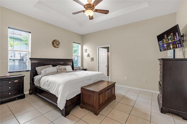 bedroom with light tile patterned floors, a tray ceiling, and ceiling fan