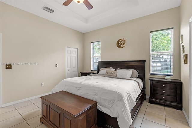 bedroom featuring a closet, ceiling fan, a raised ceiling, and light tile patterned floors