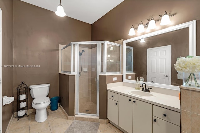 bathroom with tile patterned flooring, a shower with shower door, vanity, and toilet