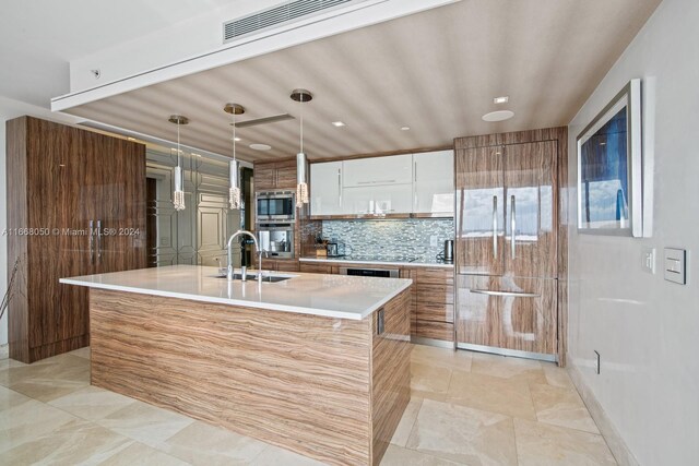 kitchen with white cabinets, an island with sink, pendant lighting, sink, and appliances with stainless steel finishes