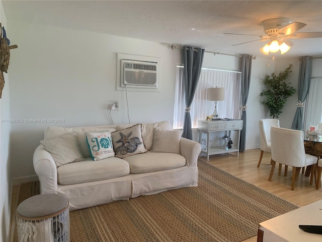 living room featuring an AC wall unit, ceiling fan, hardwood / wood-style flooring, and a textured ceiling