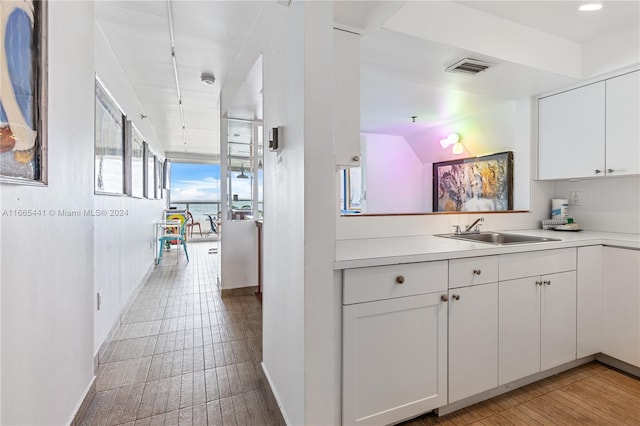 kitchen with white cabinets, light wood-type flooring, and sink