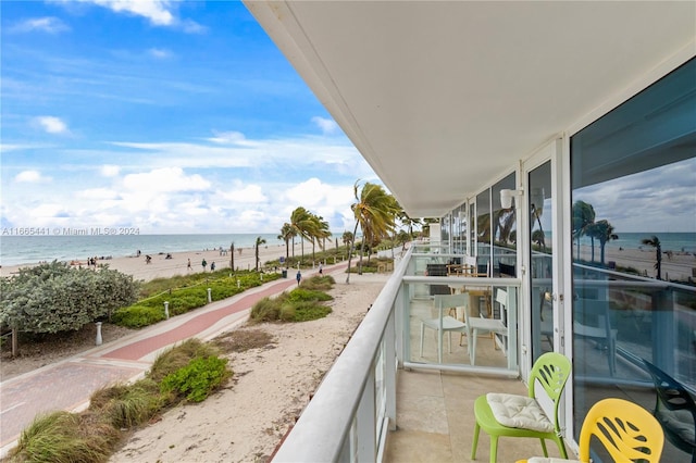 balcony featuring a view of the beach and a water view