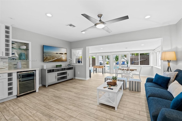 living room featuring light wood-type flooring, ceiling fan, wine cooler, and french doors