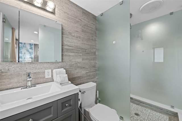 bathroom featuring vanity, toilet, a shower, tile walls, and tile patterned flooring