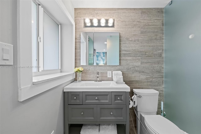 bathroom featuring tile walls, vanity, and toilet