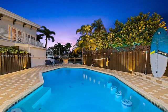 pool at dusk with a patio area