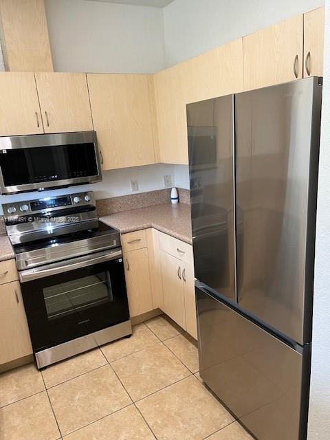 kitchen with light tile patterned floors, stainless steel appliances, and light brown cabinetry