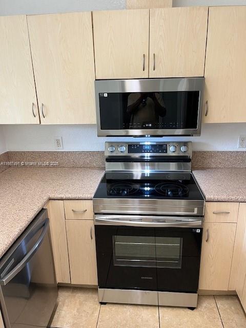 kitchen featuring light tile patterned floors, light brown cabinets, stainless steel appliances, and light countertops