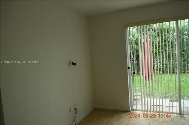 empty room featuring light tile patterned floors, baseboards, and a wealth of natural light