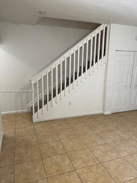 stairs featuring tile patterned floors and baseboards