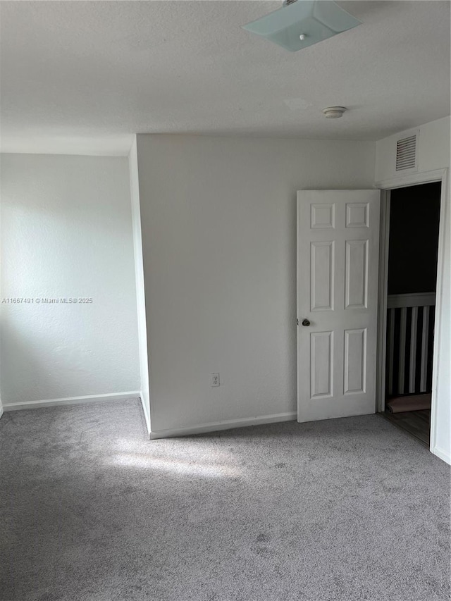 unfurnished room featuring visible vents, carpet flooring, and baseboards