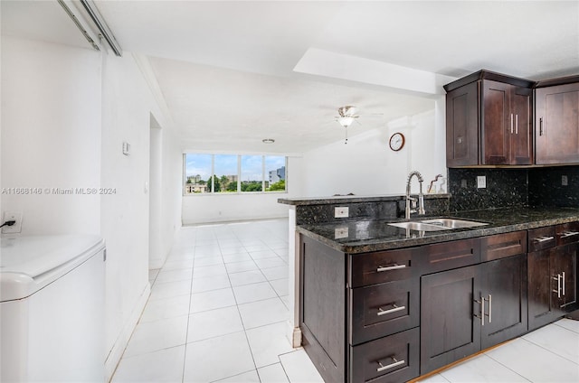 kitchen with washer / dryer, kitchen peninsula, dark stone countertops, sink, and ceiling fan