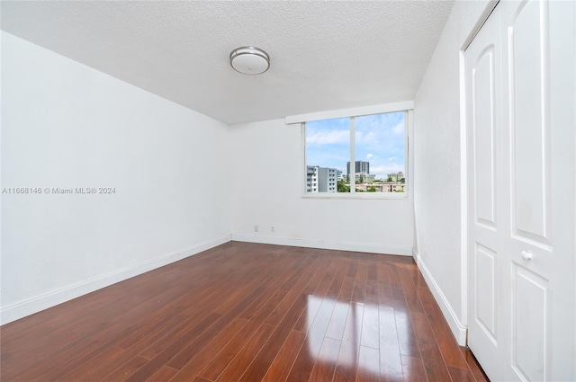 unfurnished bedroom featuring a closet, a textured ceiling, and dark hardwood / wood-style flooring