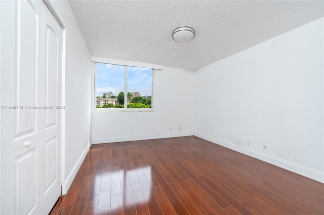 empty room with a textured ceiling and dark hardwood / wood-style floors