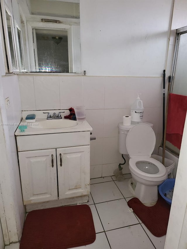 bathroom featuring tile walls, tile patterned flooring, walk in shower, vanity, and toilet