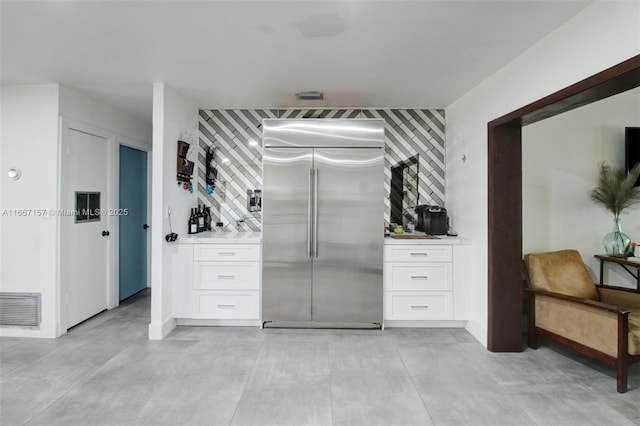 kitchen with tasteful backsplash, white cabinets, and stainless steel built in fridge