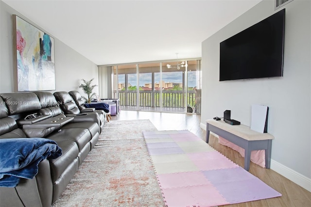 living room with a notable chandelier, hardwood / wood-style floors, and a wall of windows