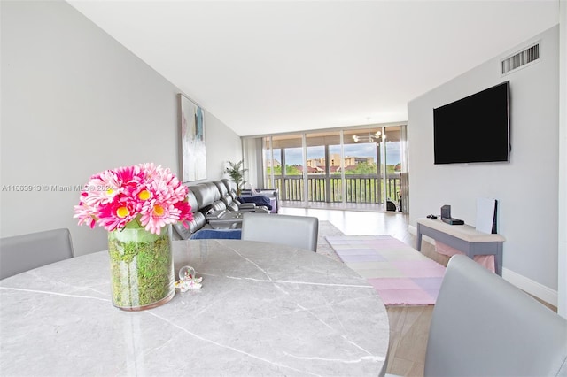 dining space with hardwood / wood-style flooring and a wall of windows