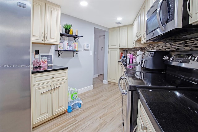 kitchen featuring appliances with stainless steel finishes, cream cabinetry, decorative backsplash, and light hardwood / wood-style floors