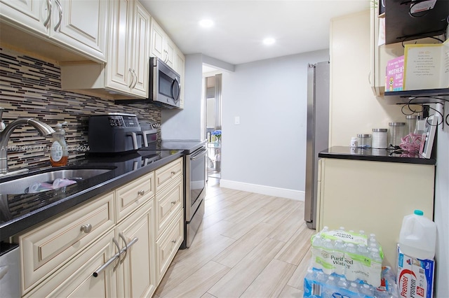 kitchen featuring appliances with stainless steel finishes, decorative backsplash, sink, and light wood-type flooring