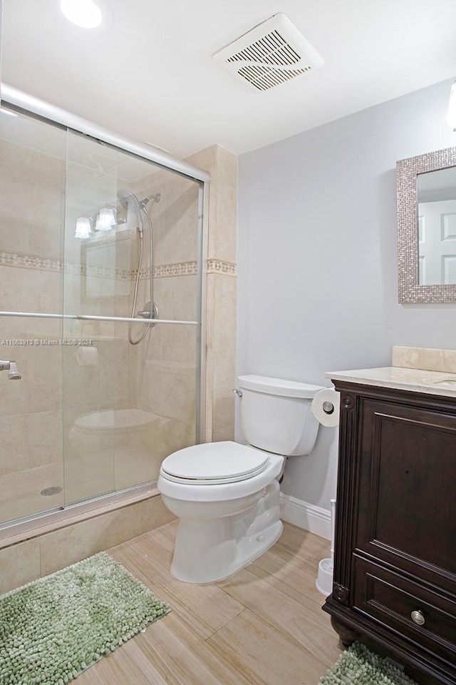 bathroom featuring a shower with door, vanity, and toilet