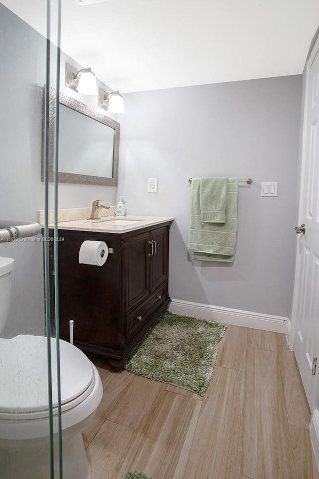 bathroom with vanity, toilet, and hardwood / wood-style flooring