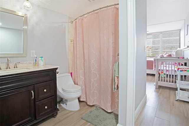 bathroom featuring toilet, hardwood / wood-style floors, walk in shower, and vanity