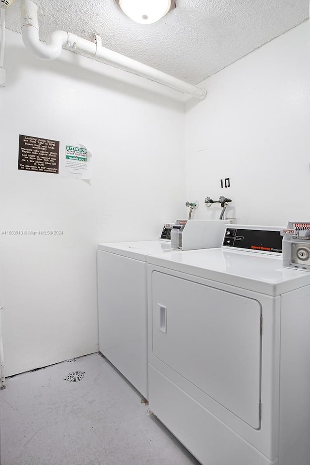 laundry room with a textured ceiling and washer and clothes dryer