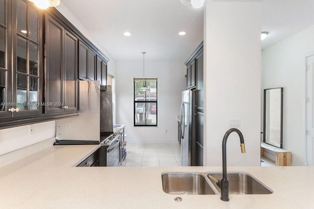 kitchen featuring appliances with stainless steel finishes, hanging light fixtures, light tile patterned floors, dark brown cabinetry, and sink