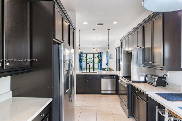 kitchen with kitchen peninsula, light tile patterned floors, stainless steel appliances, decorative light fixtures, and sink