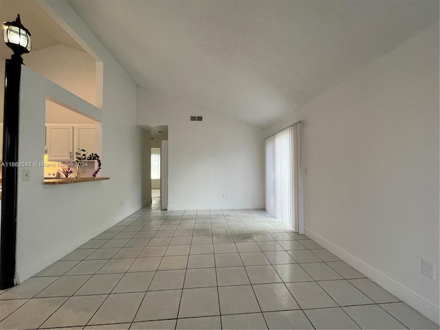 unfurnished room featuring a textured ceiling, light tile patterned floors, and high vaulted ceiling