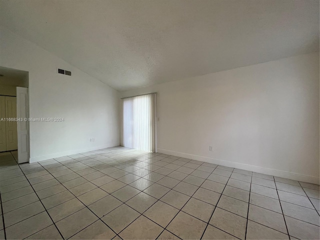 tiled empty room with vaulted ceiling