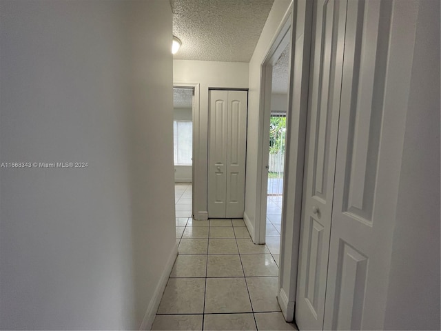 corridor with light tile patterned flooring, plenty of natural light, and a textured ceiling