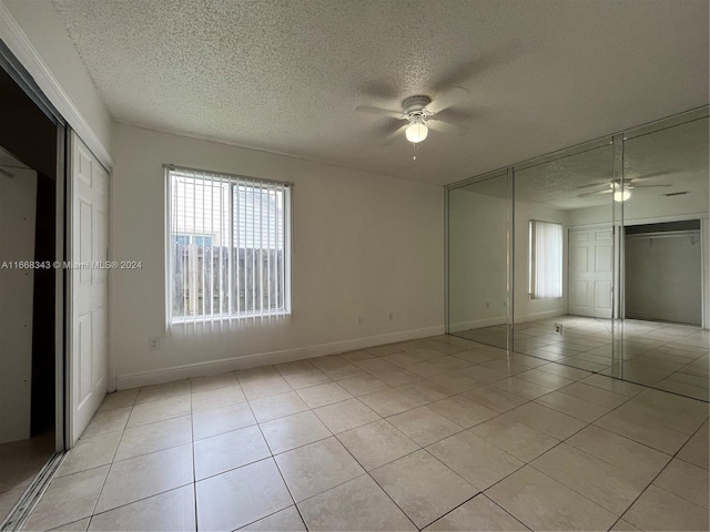 unfurnished bedroom with a textured ceiling, light tile patterned flooring, and ceiling fan