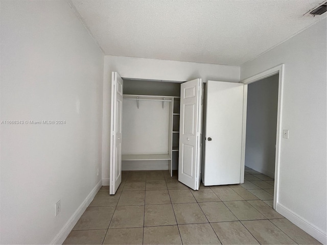 unfurnished bedroom with a closet, light tile patterned floors, and a textured ceiling