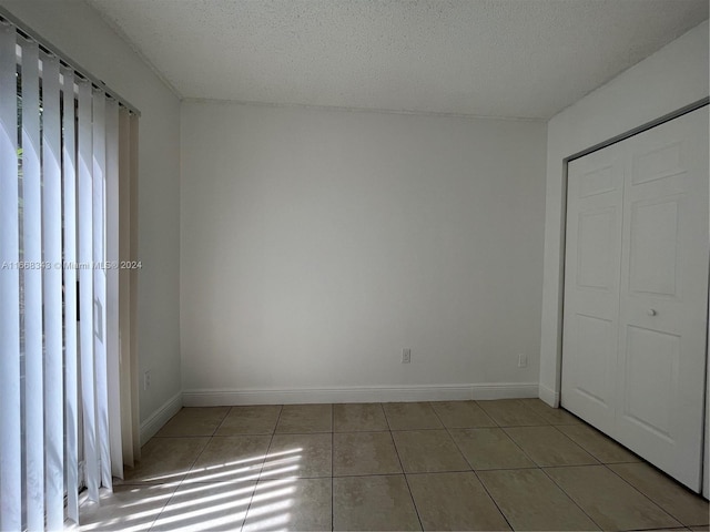 unfurnished bedroom with a textured ceiling, a closet, and tile patterned floors