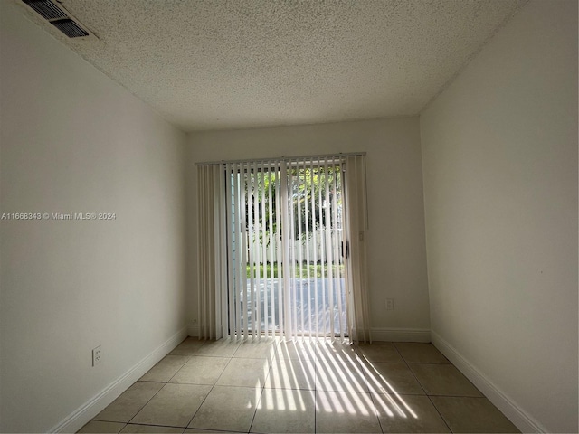 empty room featuring a textured ceiling and light tile patterned floors