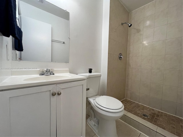 bathroom with vanity, tile patterned floors, toilet, and tiled shower