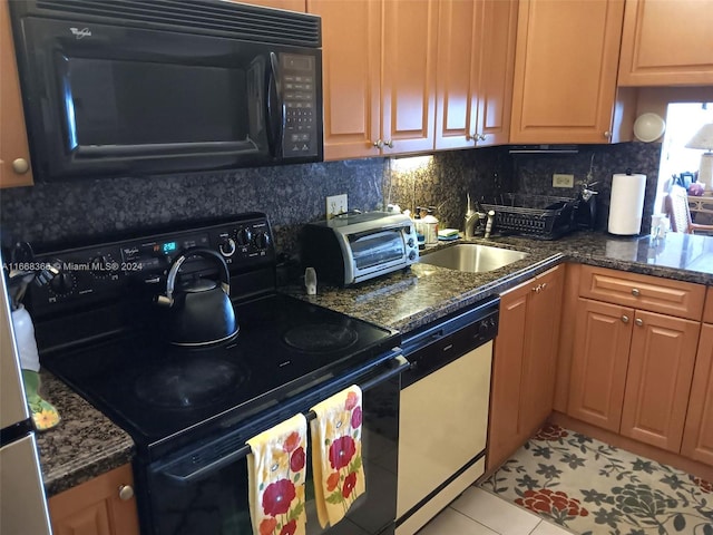 kitchen with light tile patterned flooring, sink, tasteful backsplash, black appliances, and dark stone countertops